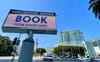 The LA convention center with green glass walls and a signboard in front that says BOOK YOUR EVENT HERE