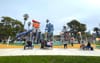 Kids and families playing at a colorful new playground with tall towers and a giant slide at LA's MacArthur Park
