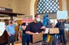 Protesters holding signs that say "Don't delay our train" in the foyer of Union Station