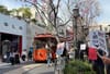 Anti-Tesla protesters hold up signs at the Americana mall across from the Tesla store as a trolley goes by