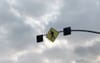 A pedestrian crossing sign with flashing lights, now dark, shown against an ominous gray sky