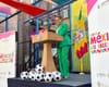 Mayor Karen Bass is in a soccer-pitch green suit standing at a city of LA podium with soccer balls and Casa Mexico banners