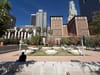 The empty park and dead trees of Pershing Square with the towers of downtown behind, although one lucky person found a bit of shade
